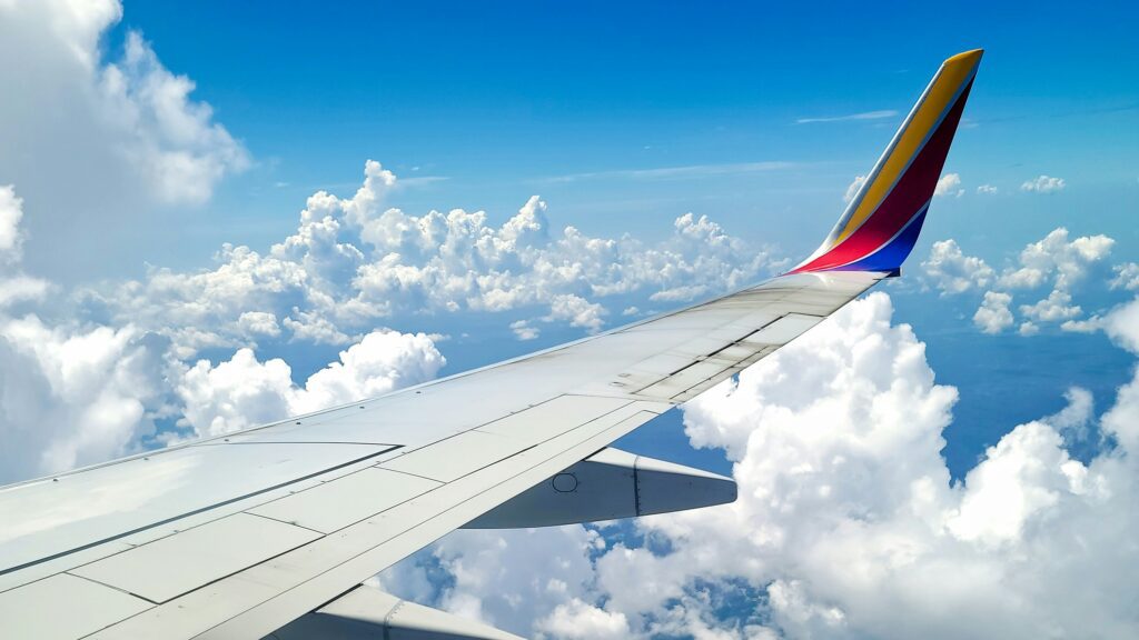 Aeroplane wing above clouds taken from inside window.