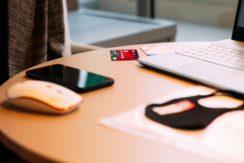 Smartphone, mouse, credit card and laptop on desk.