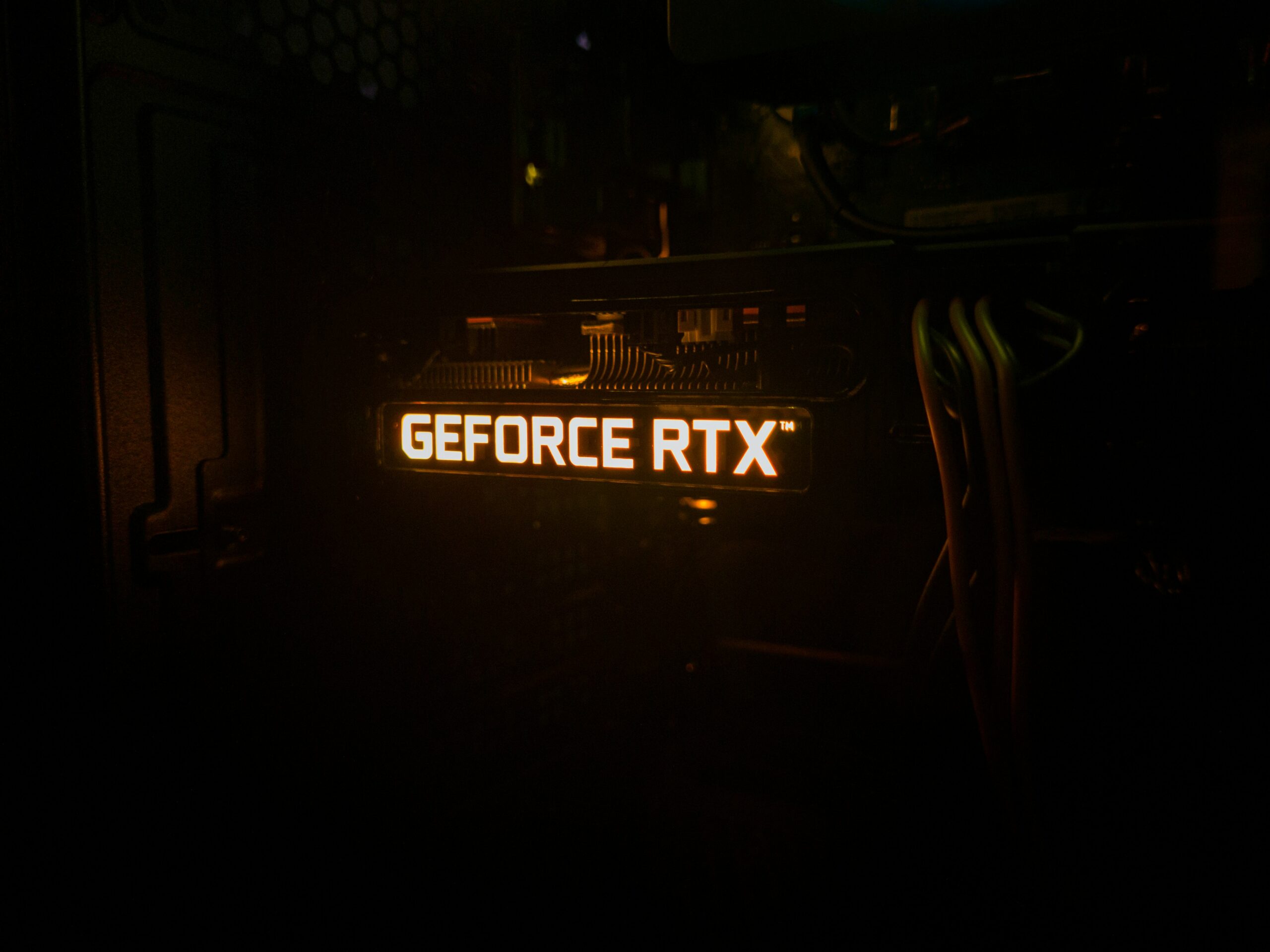 LED from GPU in pitch black lit up in orange reading Geforce RTX.