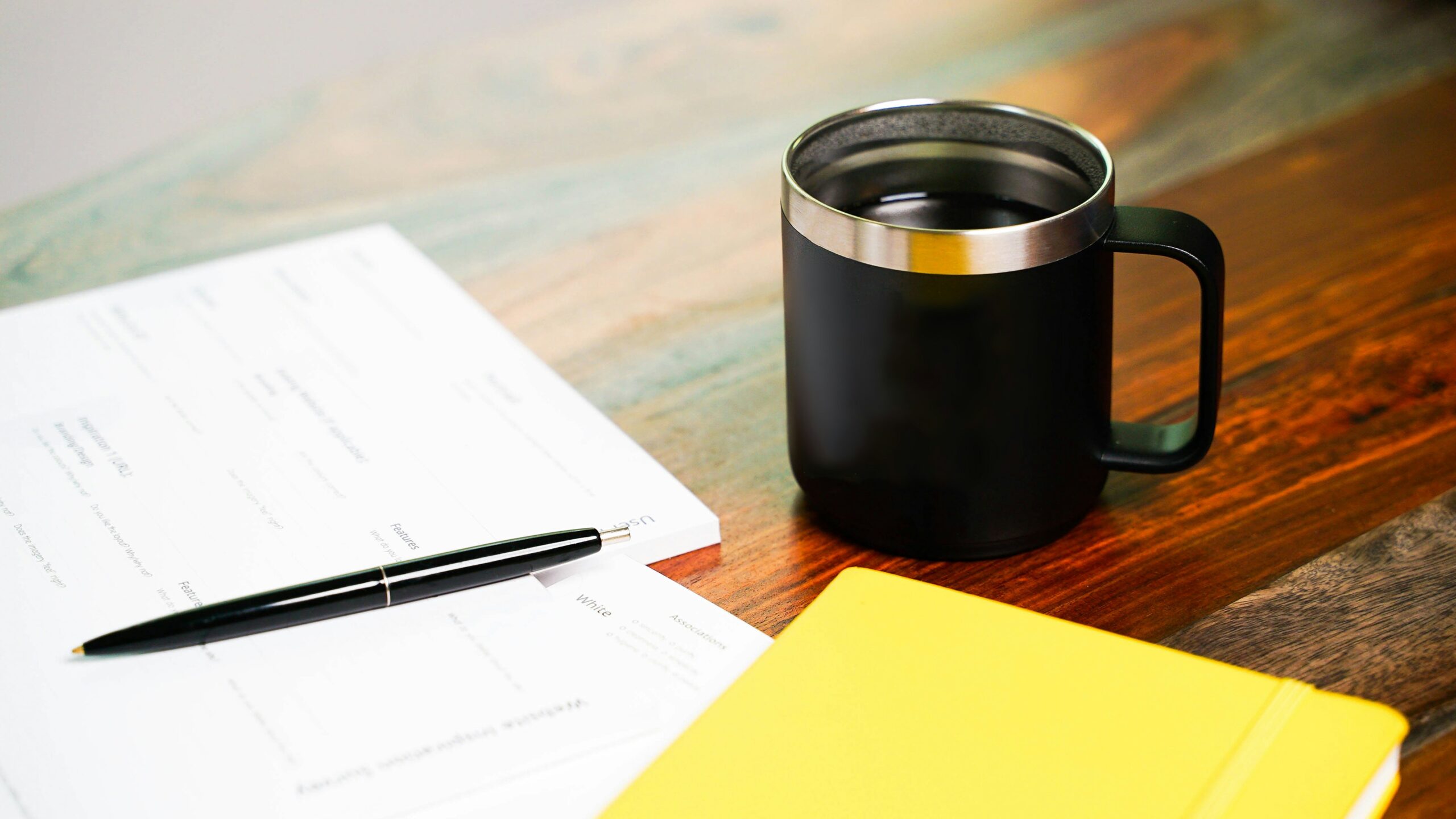 Paperwork, pen, yellow sticky notes and mug of coffee on desk.