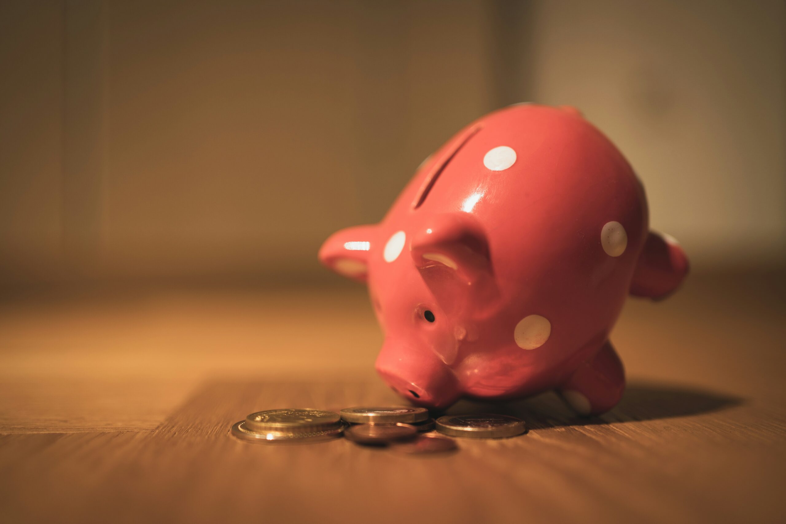 Tipped forward piggy bank with coins that have fell out.