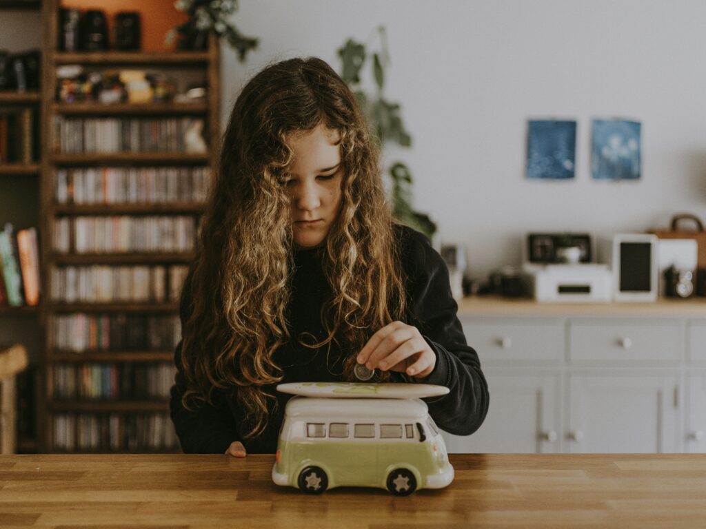 Girl putting coin in piggybank.